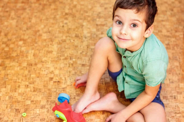 Мальчик играет с игрушками на теплом чистом полу дома. Пробковый пол — стоковое фото