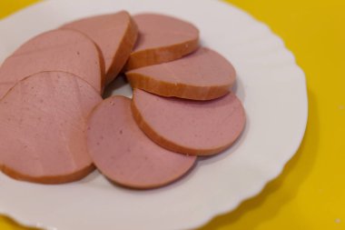 Beyaz tabakta dilimlenmiş lezzetli sosis.