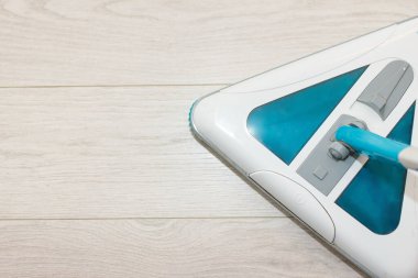 Hafif laminatın arka planında elektrikli süpürge. Yerler temiz. Dezenfekte. Konsept temizlik şirketi. Mesaj için yer var. Üst Görünüm