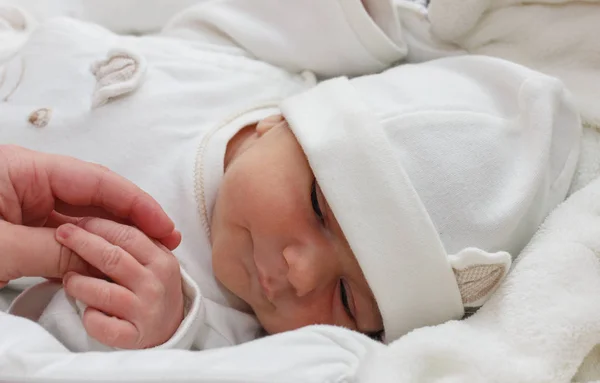 Bebé semanal toma de la mano. Bebé vistiendo una ropa blanca. Bebé recién nacido, tener una semana . — Foto de Stock