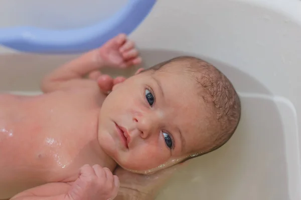 Bebé recién nacido tomando un baño. Endurecimiento, higiene del recién nacido . — Foto de Stock