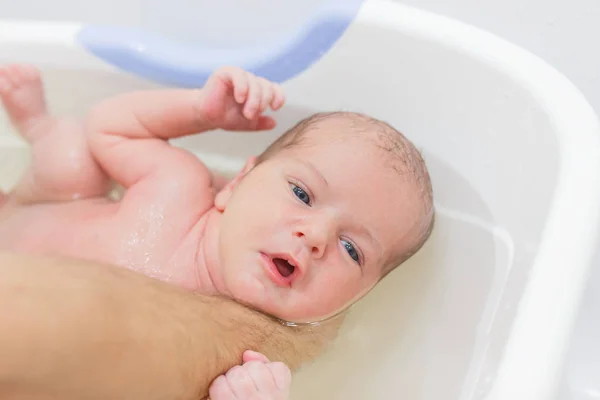 Bebé recién nacido tomando un baño. Endurecimiento, higiene del recién nacido . — Foto de Stock