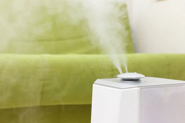 Humidifier works in the room around with a green sofa. Climatic systems. Home microclimate concept. Space for text — Stock Photo, Image