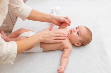 Masör küçük bebeğe masaj yapıyor, krem sıkıyor. hipertoniklik düzeltmesi