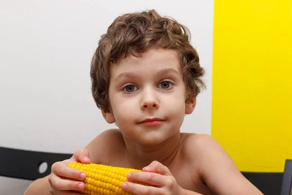 Beau garçon bouclé manger une épi de maïs bouilli, sans OGM — Photo