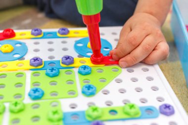 Çocuk tornavida kullanmayı öğreniyor. Çok renkli vidalar. Gelecekteki işgal kavramı