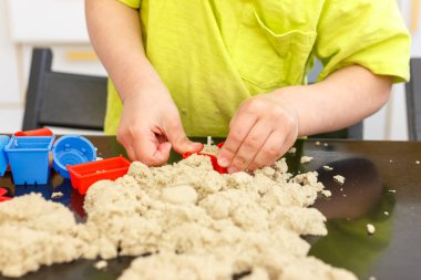 3 yaşındaki sevimli küçük çocuk evde kinetik kum oynuyor..