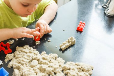 3 yaşındaki sevimli küçük çocuk evde kinetik kum oynuyor.