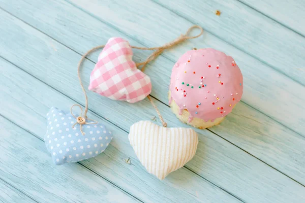 Tatlı ekmek geleneksel paskalya ortodoks pasta panettonu aynı zamanda kulich denilen pembe krema ve kuru üzüm ve mavi ahşap arka planda üç renkli kalp.