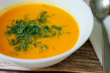 Tohumlu geleneksel balkabağı çorbası, ahşap bir masada dereotu..