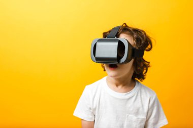 Sanal gerçeklik kulaklığı takan küçük çocuğun yakın çekimi. Sarı arka planda sanal gerçeklik gözlüğü takan çocuk..