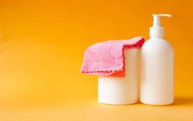 İki şişe ve konteynır, banyo ve mutfağın zeminini ve duvarlarını temizlemek için kullanılan ev kimyasalları. Sarı arkaplanda temizlik kavramı..