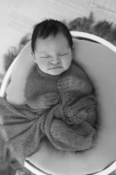 Bebé recién nacido envuelto en una manta durmiendo en una canasta. concepto de infancia, salud, FIV. Foto en blanco y negro —  Fotos de Stock