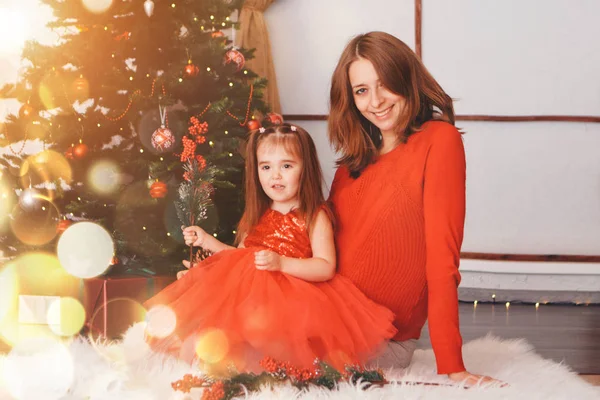 Mother and daughter in red clothes under the Christmas tree. the concept of celebrating Christmas midnight Royalty Free Stock Images