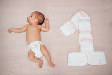 Sırtüstü yatan küçük bir kız. Havludan sarılmış bir figür. Büyüme konsepti, Ivf, çocukluk.