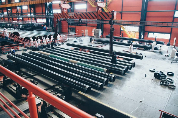 10.2019. Moskova 'daki boru üretim tesisi: ağır sanayi konsepti, inşaat makineleri - büyük bir odanın içindeki uzun metal borular. Hangarda inşaat malzemeleri