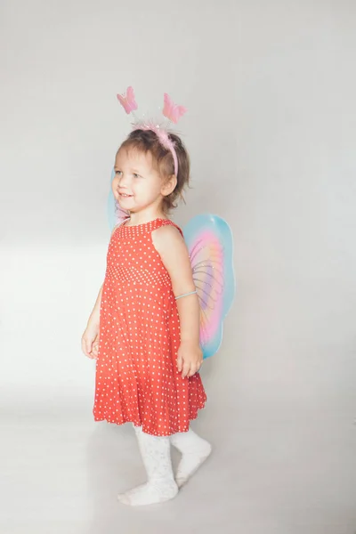 A little girl with colorful wings. A child in a fairy costume. Christmas concept, mystical creatures, Halloween, carnival, costume party — Stock Photo, Image