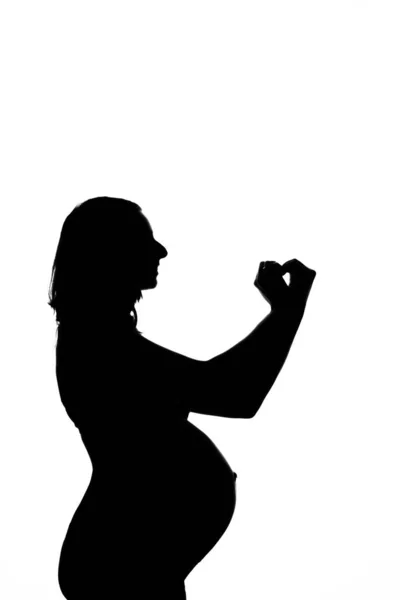 Silhouette di una donna incinta su sfondo bianco. La futura mamma mostra il segno del cuore con le mani. Il concetto di uno stile di vita sano, fecondazione in vitro, espressione di emozioni, gesti. Copia spazio — Foto Stock