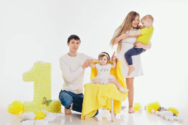 Narozeniny oslava: rodina sedí na podlaze mezi dekoracemi: čísla 1, umělé květiny a bílé koule — Stock fotografie