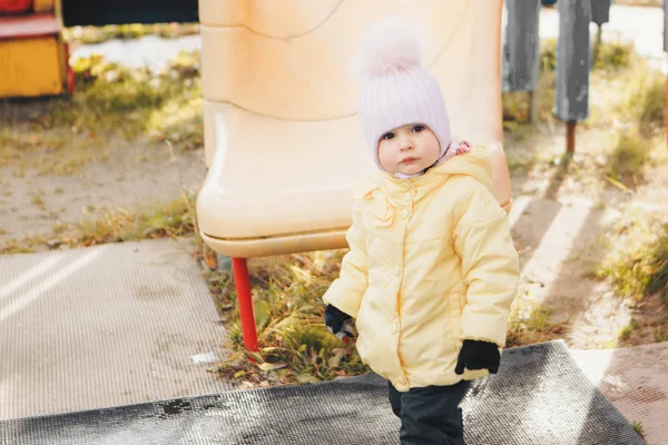 En liten flicka som leker på lekplatsen i barnens stad. Ett litet barn rider nedför kullen, på karusellen, klättrar uppför repen. Underhållningsindustri, familjedag, barnparker — Stockfoto