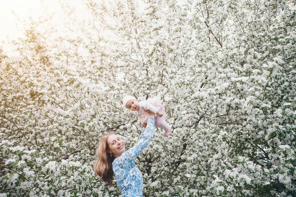 beautiful woman holding children. March 8: women among flowers. the concept of congratulations, women's holidays, natural make up