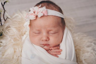 Saçbandında çiçekle uyuyan yeni doğmuş bir bebeğin portresi. Sağlık konsepti: Ivf, bebek aksesuarları
