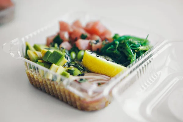 Japanese cuisine: fish, lemon, onion, avocado in a plastic container. Advertising concept of traditional Oriental cuisine — Stock Photo, Image