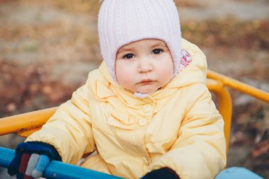 Küçük bir kız çocuk parkında oyun oynuyor. Küçük bir çocuk tepeden aşağı atlıkarıncaya biner, iplere tırmanır. Eğlence sektörü konsepti, aile günü, çocuk parkları