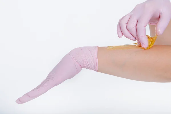 Manos en guantes de goma de cerca. El doctor pone cera, cariño. Médico se está preparando para la depilación. Concepto de medicina, instrumentos médicos, cuidado de la salud, industria de la belleza, depilación, material natural — Foto de Stock