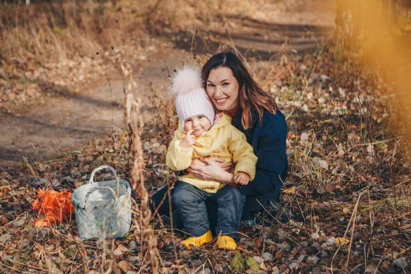 Malé dítě s matkou v teplém obleku procházející se v lese. Žena a dívka sbírat listy v košíku podzim Park. Koncept chůze na čerstvém vzduchu, sběr ovoce: houby, zelenina — Stock fotografie