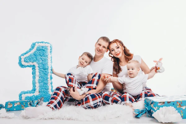 Geburtstagsfeier: Familie sitzt auf dem Boden inmitten der Dekoration: Ziffern 1, künstliche Blumen und Geschenke. Geburtstag, Feiertage. Kopierraum — Stockfoto