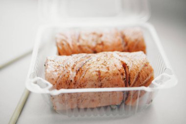 Japon mutfağı: plastik bir kapta rulo. Beyaz arka planda suşi. Geleneksel Doğu mutfağı reklam kavramı, balık yemi: somon, ton balığı, pirinç