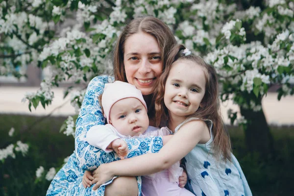 Hermosa mujer sosteniendo niños. 8 de marzo: mujeres entre flores. el concepto de felicitaciones, vacaciones de mujeres, maquillaje natural —  Fotos de Stock