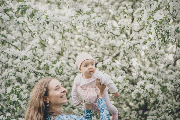 beautiful woman holding children. March 8: women among flowers. the concept of congratulations, women\'s holidays, natural make up