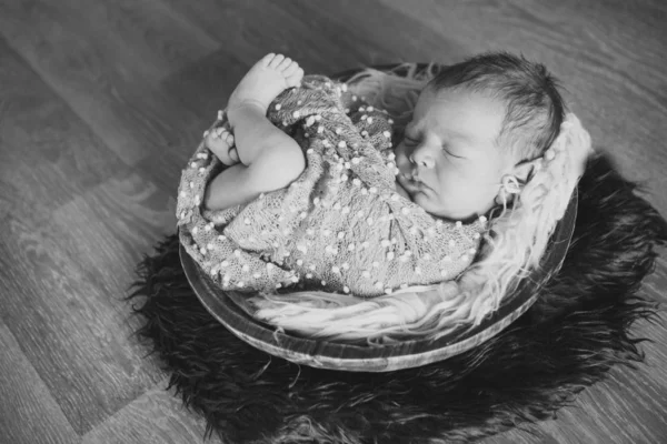 Νεογέννητο μωρό τυλιγμένο σε μια κουβέρτα που κοιμούνται σε ένα καλάθι. έννοια της παιδικής ηλικίας, της υγειονομικής περίθαλψης, της γονιμοποίησης. Μαύρη και λευκή φωτογραφία — Φωτογραφία Αρχείου