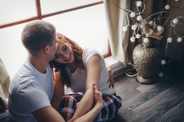 Sevgi dolu bir çift, dekoratif bir vazonun yanında yere sarılıyor. Bir erkek ve bir kadın birbirlerinin gözlerinin içine bakar. Sevgililer Günü. 14 Şubat