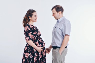 Beyaz bir arka planda birbirini seven bir çift. Bir erkek ve bir kadın birbirlerinin gözlerinin içine bakar. Koca hamile karısına sarılıyor. Sevgililer Günü. 14 Şubat