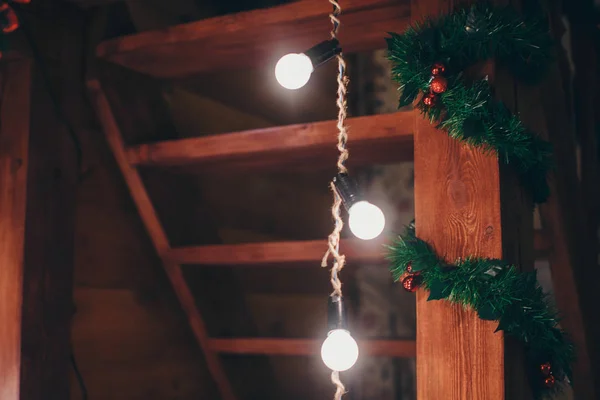 Şenlikli iç mekan: Ahşap dekorlar arasında Noel süsleri ve ampuller. Noel ve Yeni Yıl konsepti, tatil oyuncakları, çelenk ve ışıklandırma — Stok fotoğraf