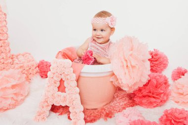 Doğum günü kutlaması: çocuk yerde madalyonun yanında oturuyor: 1 numara, yapay çiçekler ve hediyeler. Doğum günü konsepti, tatiller. Boşluğu kopyala