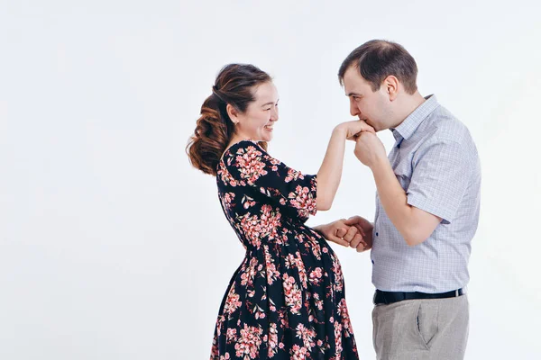 Kärleksfullt par omfamna på en vit bakgrund. En man och en kvinna ser varandra i ögonen. Maken kramar gravid fru. Alla hjärtans dag. 14 februari — Stockfoto