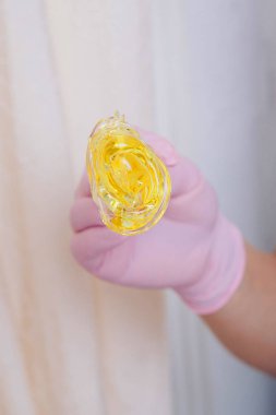 Yakından tüy dökmek için balmumu. Kız kozmetik ürünler sergiliyor. Doktorun eldivenli eli. Şekerleme: Sıvı şekerli saç kesimi. Bu daha az acılı bir tüy dökücü.