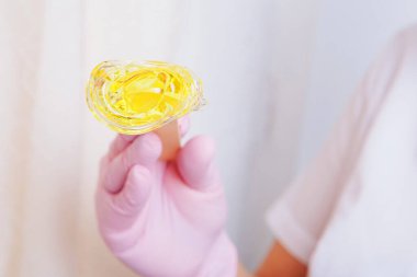 Yakından tüy dökmek için balmumu. Kız kozmetik ürünler sergiliyor. Doktorun eldivenli eli. Şekerleme: Sıvı şekerli saç kesimi. Bu daha az acılı bir tüy dökücü.