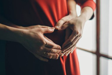 Heart symbol folded from the hands. a pregnant woman is stroking her stomach. Copy space. Healthy lifestyle concept, IVF, mother's day, international women's day, Valentine's day