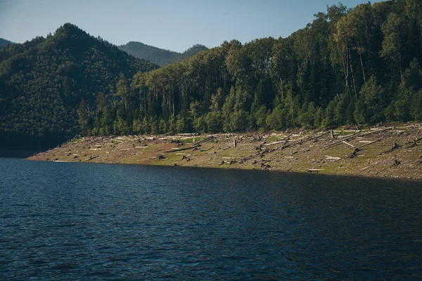 the concept of boating, recreation, travel - splashes of blue water in the river, mountains, sky, stone shore. Copy space