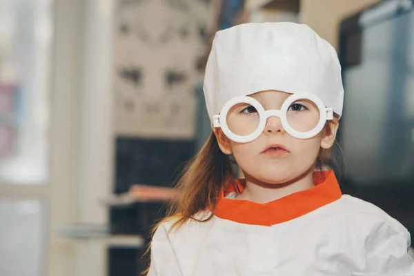 stock image a little girl in a doctor's suit. The child is playing doctor. White coat, glasses, cap with a red cross, medical equipment. Concept of a healthy lifestyle, health care, medicine