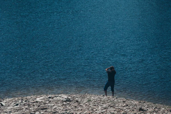 Hombre Está Sentado Las Rocas Junto Lago Mujer Tomando Sol —  Fotos de Stock