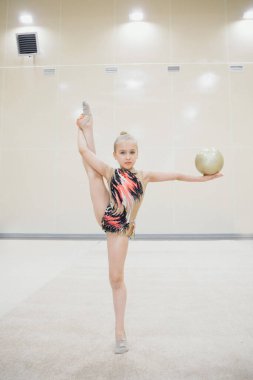 A girl in a tracksuit doing exercises with ball on a white background. Healthy lifestyle concept, sports uniforms, world Cup, gym, specialized clothing, uniforms
