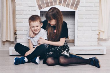 the concept of a healthy lifestyle , child protection, home interior - these are teenagers playing together. Happy children: brother and sister by the fireplace