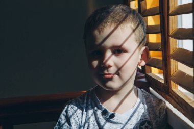 Pencerenin yanındaki çocuk. Çocuk dışarı bakıyor. Yaşam tarzı kavramı, tatiller