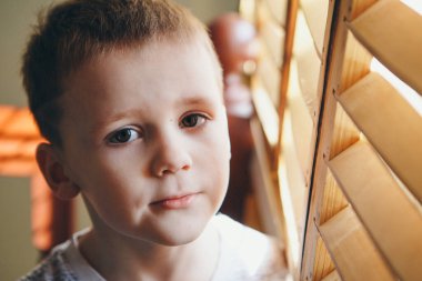 Pencerenin yanındaki çocuk. Çocuk dışarı bakıyor. Yaşam tarzı kavramı, tatiller